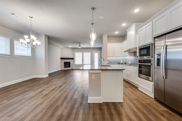 kitchen with white cabinets, built in appliances, dark hardwood / wood-style floors, and an island with sink