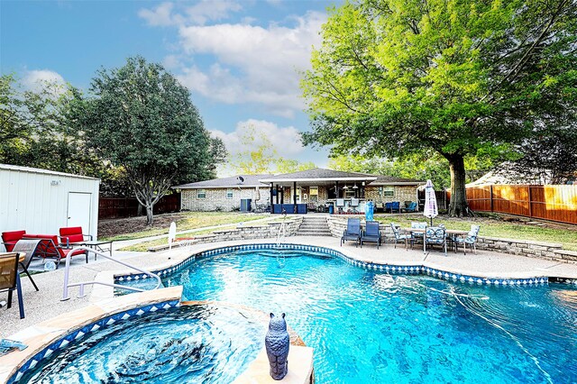 view of pool with a patio, an outdoor hot tub, and a shed