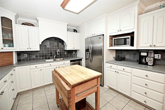 kitchen featuring appliances with stainless steel finishes, white cabinetry, sink, backsplash, and light tile patterned floors