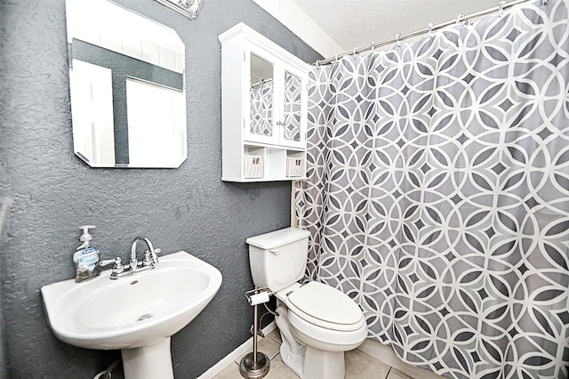 bathroom with tile patterned floors, toilet, sink, a textured ceiling, and curtained shower