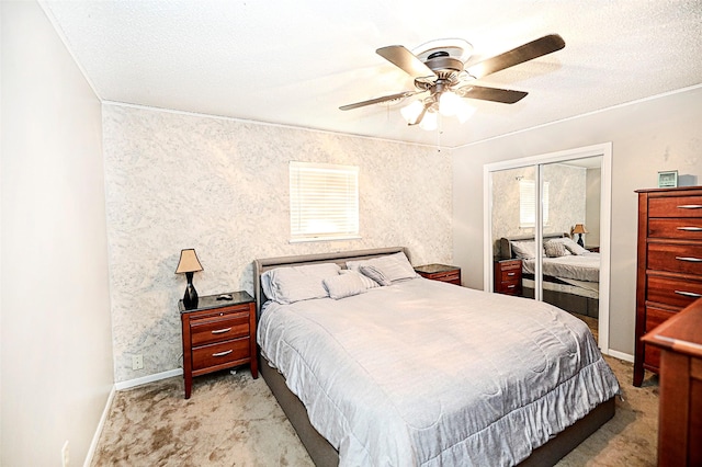 bedroom featuring a textured ceiling, light colored carpet, a closet, and ceiling fan