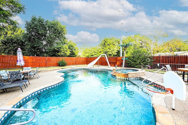 view of swimming pool with an in ground hot tub, a water slide, and a patio area