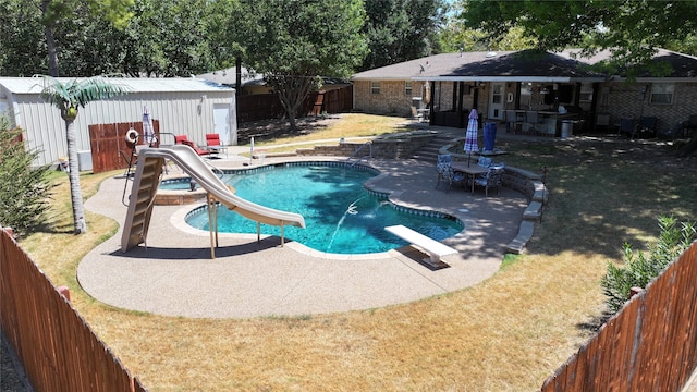 view of swimming pool with a patio area, a lawn, a diving board, and a water slide