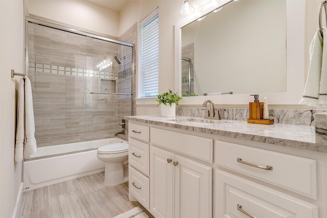 full bathroom featuring shower / bath combination with glass door, toilet, a healthy amount of sunlight, and vanity