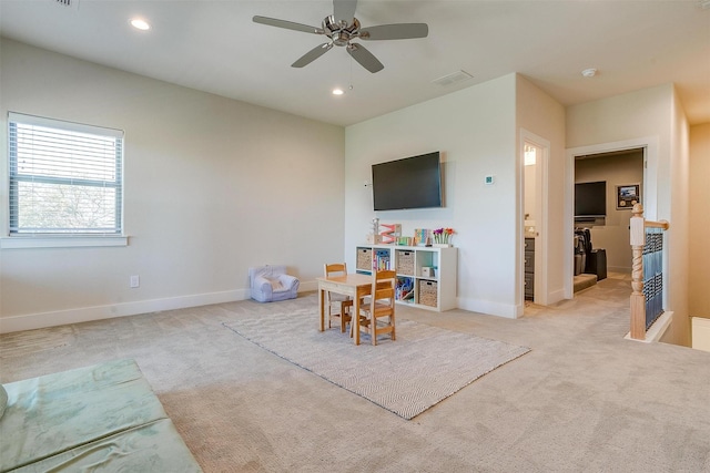 recreation room with ceiling fan and light carpet