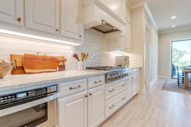 kitchen with stainless steel appliances, white cabinets, decorative backsplash, and light stone countertops