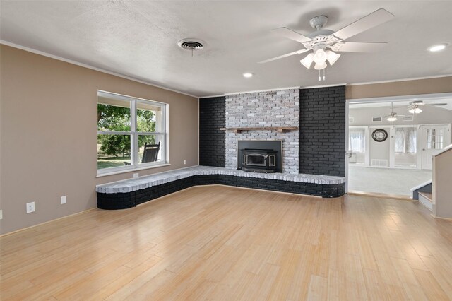 unfurnished living room featuring a fireplace, crown molding, ceiling fan, and light hardwood / wood-style floors