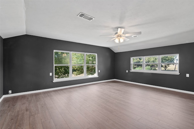 unfurnished room featuring a wealth of natural light, ceiling fan, hardwood / wood-style flooring, and vaulted ceiling