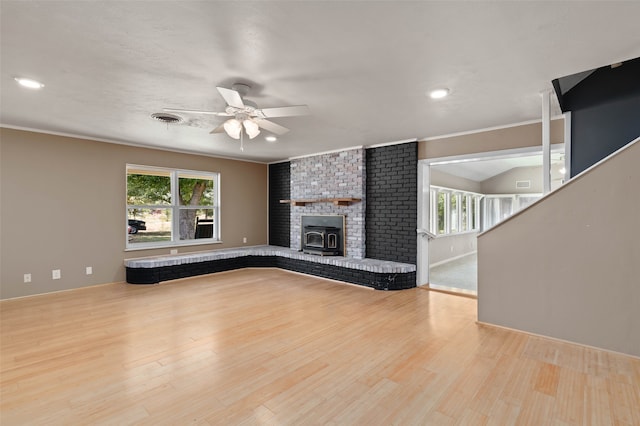 unfurnished living room with ceiling fan, a wealth of natural light, a fireplace, and light hardwood / wood-style flooring