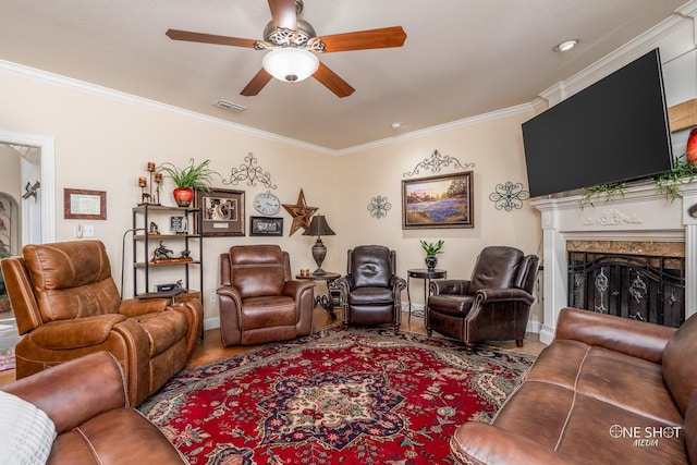 living room featuring ceiling fan, ornamental molding, and a fireplace