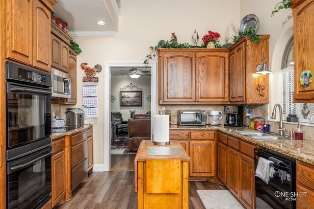 kitchen with a center island, sink, dark wood-type flooring, crown molding, and black appliances