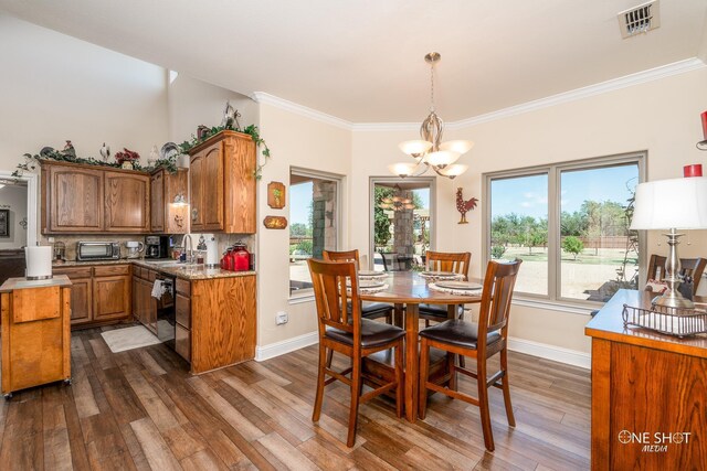 kitchen featuring pendant lighting, an inviting chandelier, sink, ornamental molding, and dark hardwood / wood-style flooring