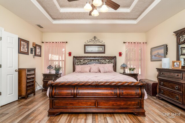 bedroom featuring a tray ceiling, crown molding, and light hardwood / wood-style floors