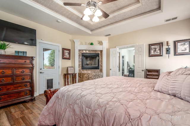 bedroom featuring a raised ceiling, crown molding, hardwood / wood-style floors, and ceiling fan