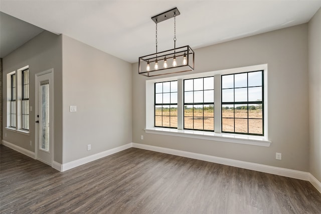 spare room with dark hardwood / wood-style floors and a chandelier