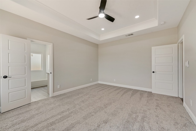 unfurnished bedroom featuring ceiling fan, a raised ceiling, and light carpet