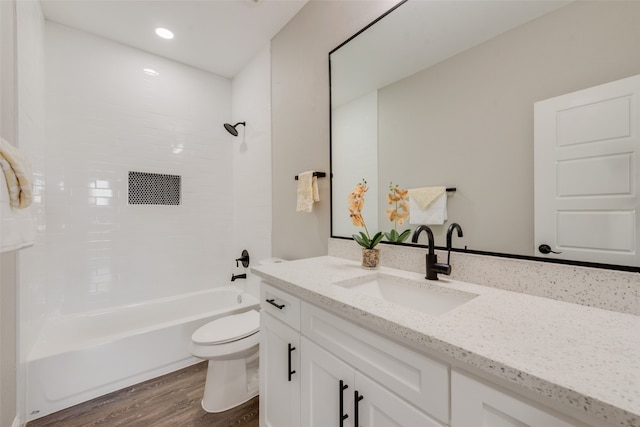 full bathroom featuring hardwood / wood-style flooring, vanity, tiled shower / bath combo, and toilet