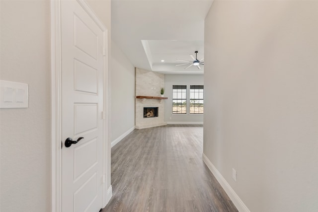 hall with hardwood / wood-style flooring, brick wall, and a tray ceiling