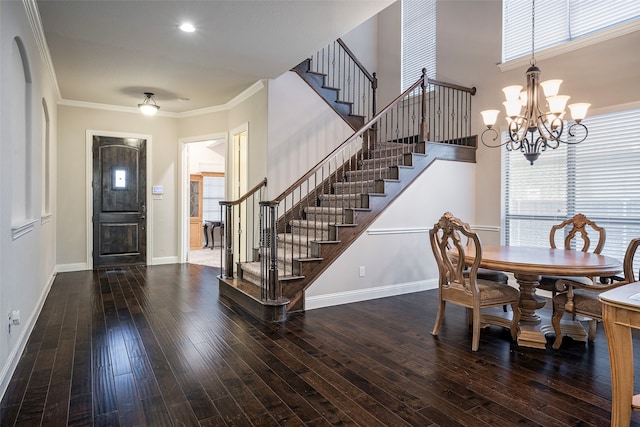 foyer entrance featuring a high ceiling, a notable chandelier, ornamental molding, and dark hardwood / wood-style flooring