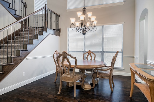 dining area featuring hardwood / wood-style floors, crown molding, an inviting chandelier, and a towering ceiling