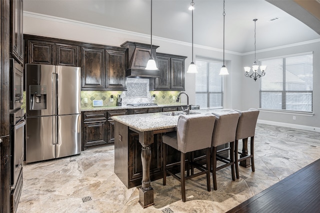 kitchen with sink, custom range hood, a kitchen island with sink, stainless steel appliances, and pendant lighting