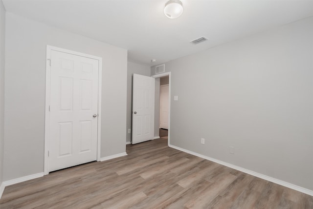 unfurnished bedroom with light wood-style flooring, visible vents, and baseboards