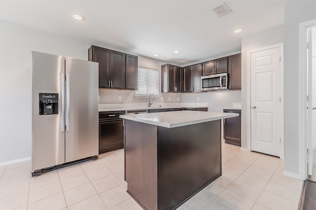 kitchen with dark brown cabinetry, appliances with stainless steel finishes, light tile patterned flooring, and a kitchen island