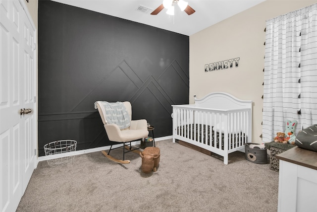 bedroom featuring ceiling fan, a crib, and carpet flooring