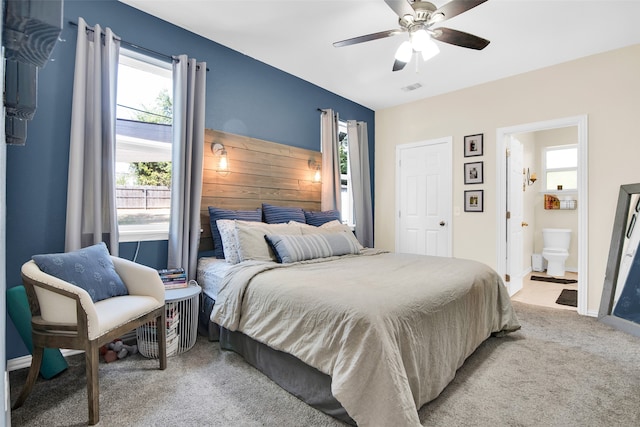 bedroom featuring ceiling fan, light carpet, and ensuite bath