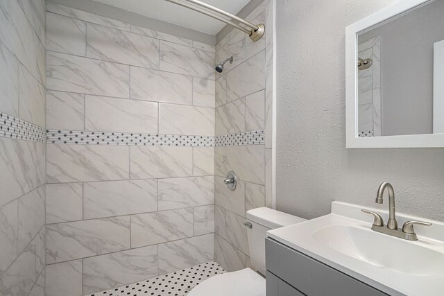 bathroom with vanity, a tile shower, and toilet