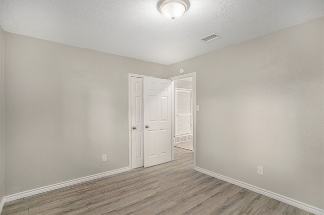 unfurnished room with light hardwood / wood-style floors and a textured ceiling