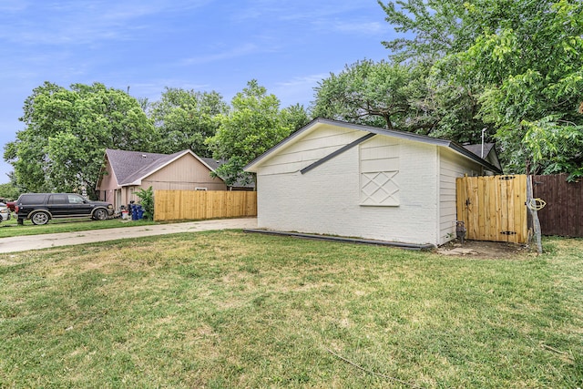 view of side of home with a yard, brick siding, and fence