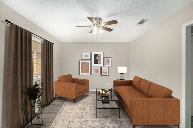 living room with a textured ceiling, ceiling fan, and light wood-type flooring