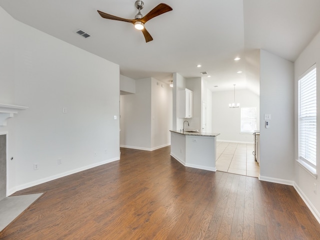 unfurnished living room featuring light hardwood / wood-style floors, ceiling fan with notable chandelier, vaulted ceiling, and sink