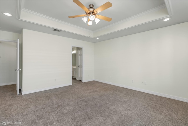 empty room featuring a tray ceiling, ornamental molding, and light colored carpet