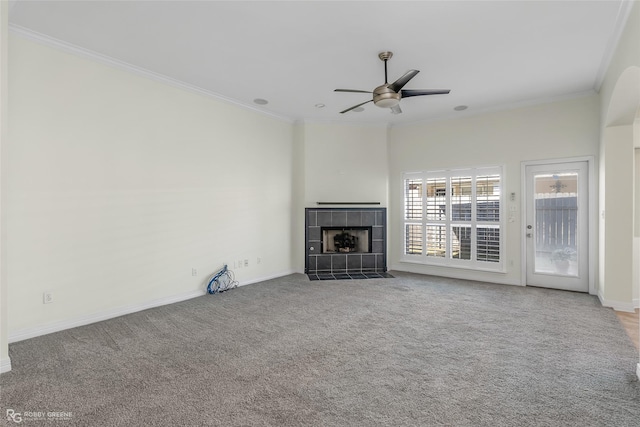 unfurnished living room featuring a tile fireplace, carpet floors, ceiling fan, and ornamental molding