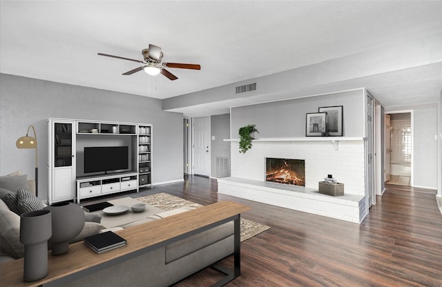 living room with dark hardwood / wood-style flooring, a brick fireplace, and ceiling fan