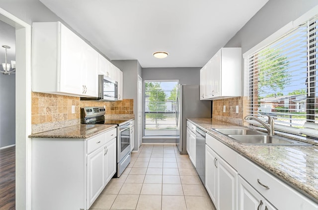 kitchen featuring tasteful backsplash, white cabinetry, appliances with stainless steel finishes, light stone countertops, and sink