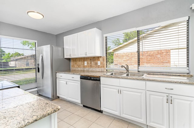 kitchen with tasteful backsplash, white cabinets, light tile patterned floors, sink, and stainless steel appliances