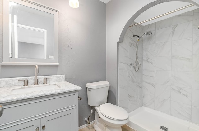 bathroom featuring toilet, a tile shower, and vanity