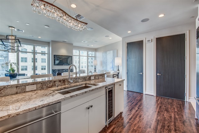 kitchen with dishwasher, light stone counters, sink, white cabinets, and dark hardwood / wood-style flooring