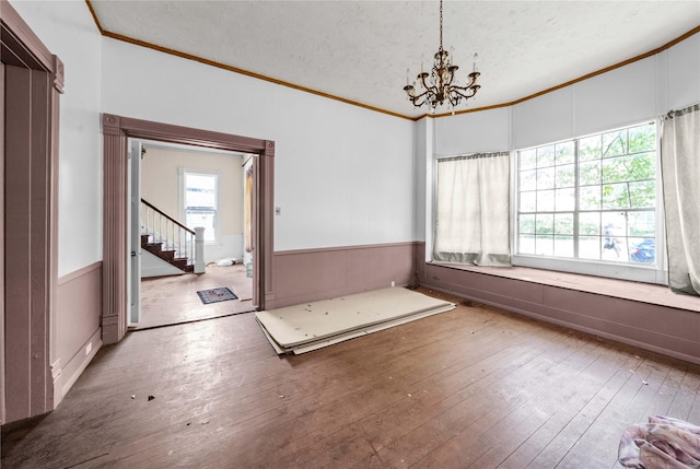 unfurnished dining area featuring a textured ceiling, hardwood / wood-style floors, and crown molding