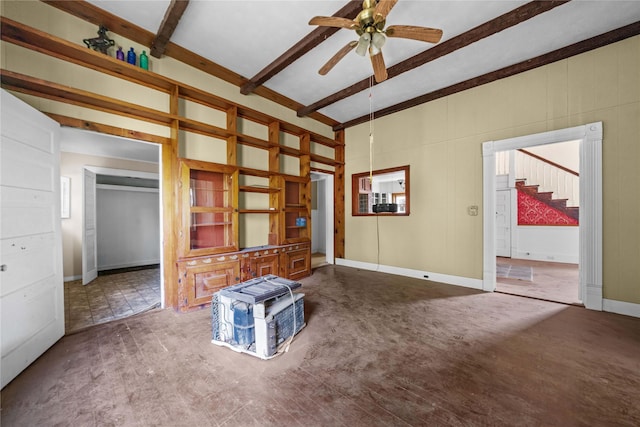 unfurnished living room featuring ceiling fan and beamed ceiling