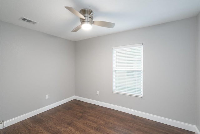 empty room featuring a ceiling fan, baseboards, visible vents, and dark wood-style flooring