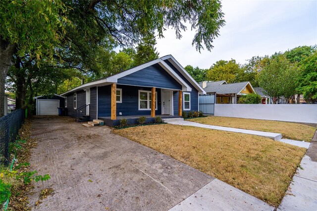 bungalow-style house featuring a garage, a front yard, an outdoor structure, and covered porch