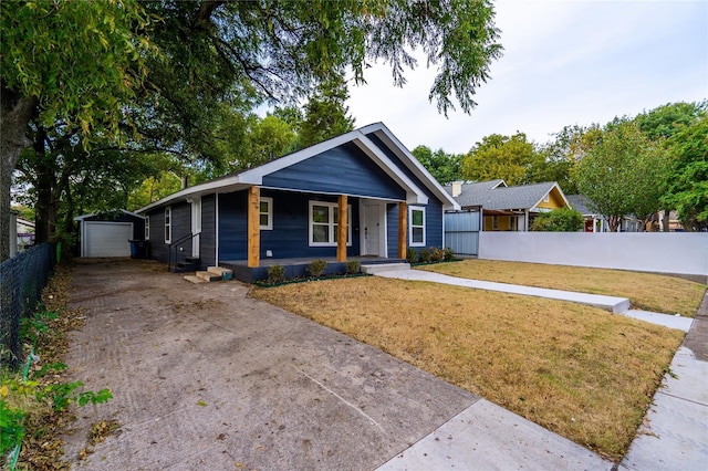 view of front of house with an outbuilding, driveway, a front lawn, and fence