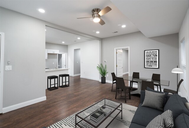 living room featuring ceiling fan and dark hardwood / wood-style floors