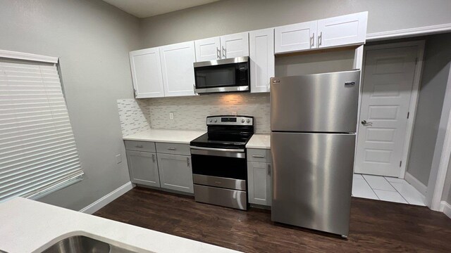 kitchen with dark hardwood / wood-style flooring, appliances with stainless steel finishes, tasteful backsplash, gray cabinetry, and white cabinetry