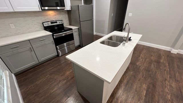 kitchen with stainless steel appliances, tasteful backsplash, sink, an island with sink, and dark hardwood / wood-style flooring