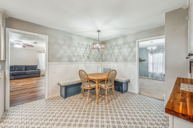 carpeted dining room with ceiling fan with notable chandelier